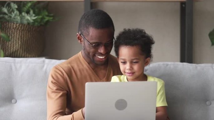 快乐的黑人父亲教孩子儿子阅读使用笔记本电脑