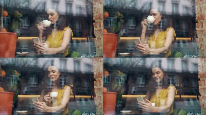 可爱的女学生在舒适的咖啡馆喝咖啡和使用智能手机