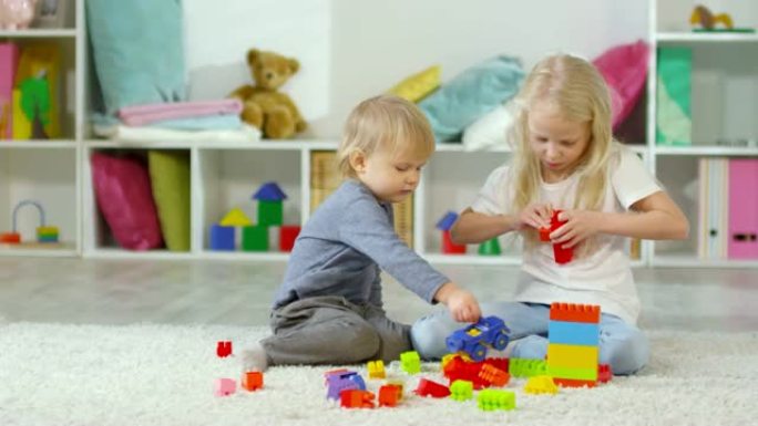 小兄弟姐妹在家里的地板上玩建筑玩具