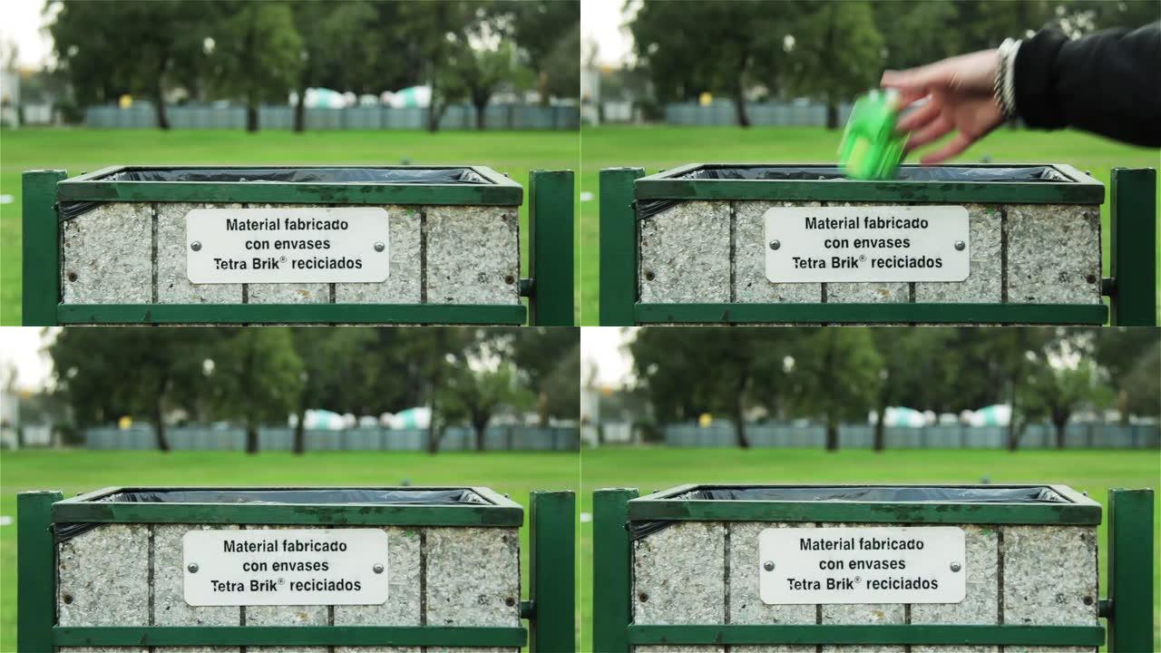 年轻人把一个罐扔进公园的回收箱。