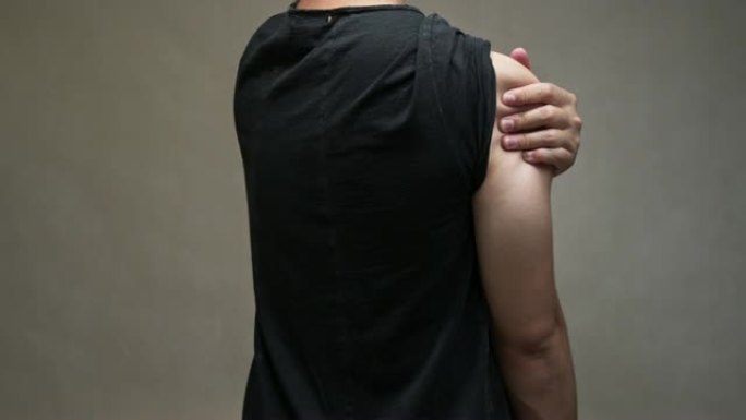 穿着黑色衬衫的亚洲男人感到肩膀疼痛。肌肉疼痛，保健概念。