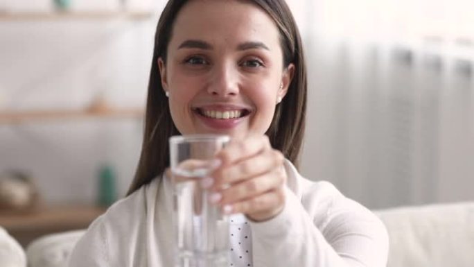 微笑的健康女人拿着一杯水看着相机