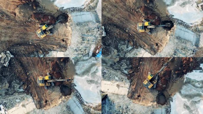 挖掘机从地面建筑物的孔中抓取土壤的俯视图，施工过程。