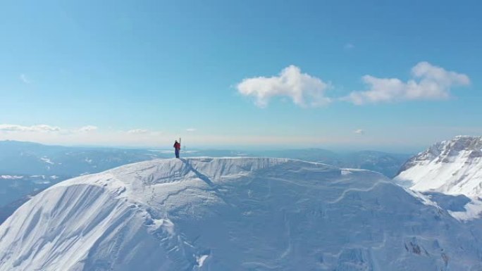 空中: 壮观的晴天山脉环绕滑雪者拍摄自然照片