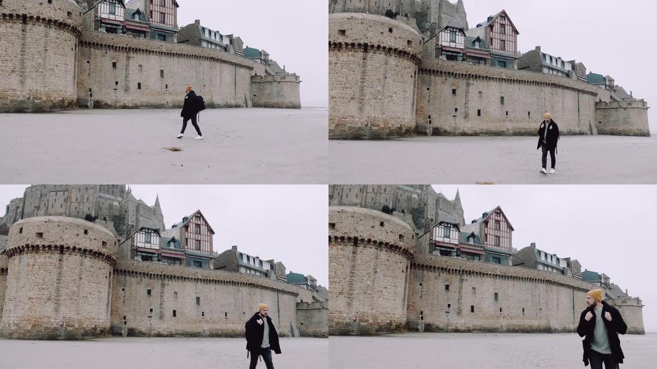 宽镜头快乐兴奋的游客，背着背包，靠近诺曼底史诗圣米歇尔山城堡慢动作。