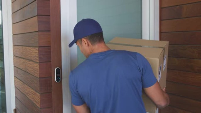男性快递员将包裹留在房屋前门外，观察封锁中的社交距离