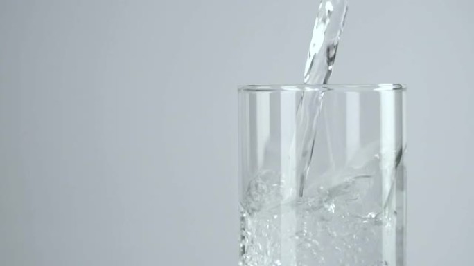 慢动作: 将水倒入白色背景的水杯中。
