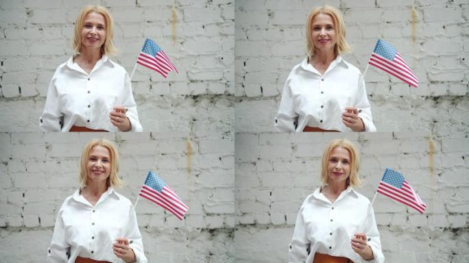 漂亮的美国女人举着美国国旗微笑在砖的背景