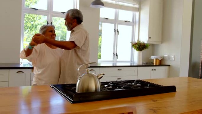 高级黑人夫妇在舒适的家庭4k厨房里一起跳舞的侧视图