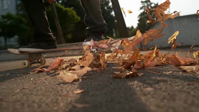 慢动作: 溜冰者在着地后用木板散射树叶。