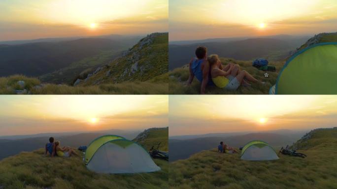 无人机: 无忧无虑的夫妇在帐篷旁放松和拥抱，观看日出。