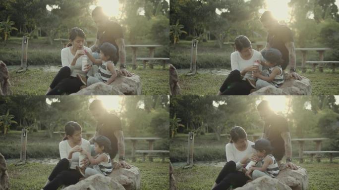 亚洲男婴和家人坐在森林里的草地上。