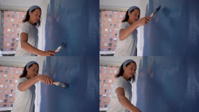 成年妇女在家里做一个DIY项目，用蓝色油漆粉刷墙壁