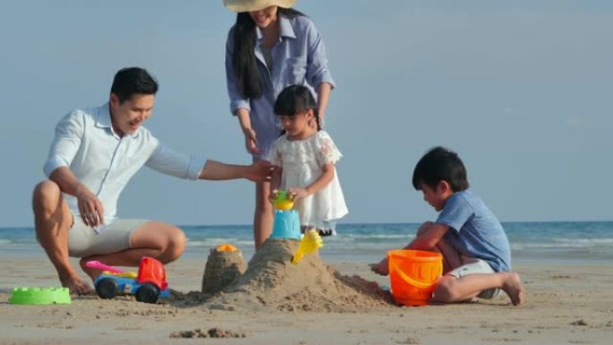 家人在沙滩上的沙箱里为孩子们玩玩具。快乐的家庭在沙滩上享受暑假。假期-iStock