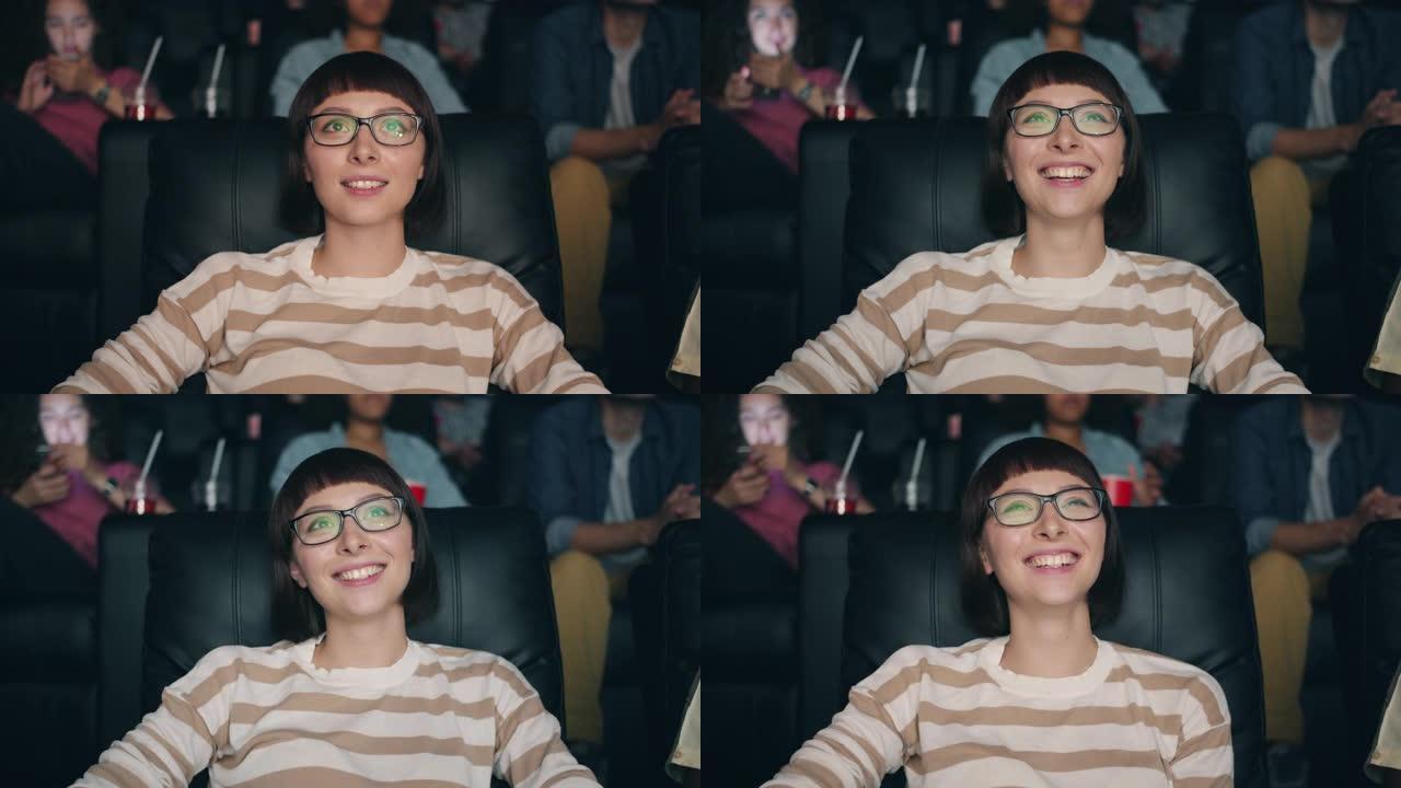 戴着眼镜的漂亮年轻女士的慢动作在电影院里笑着看电影
