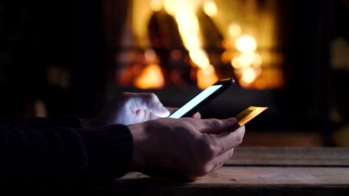一名男子向他的智能手机写信给他的朋友，妻子和家人，在背景中壁炉着火。