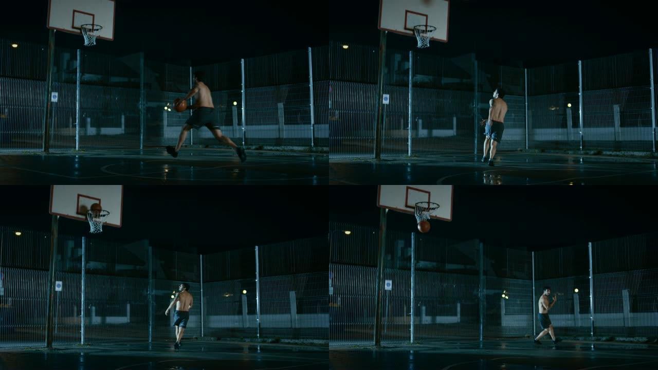 运动年轻的男子篮球运动员运球并在围栏的街球场上扔球。庆祝打进两分球。居民区雨后的夜间录像。