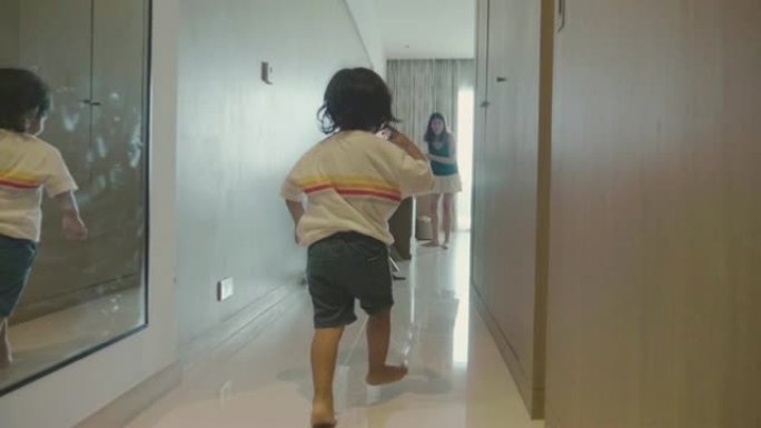 快乐的亚洲男婴跑到他母亲的酒店房间。