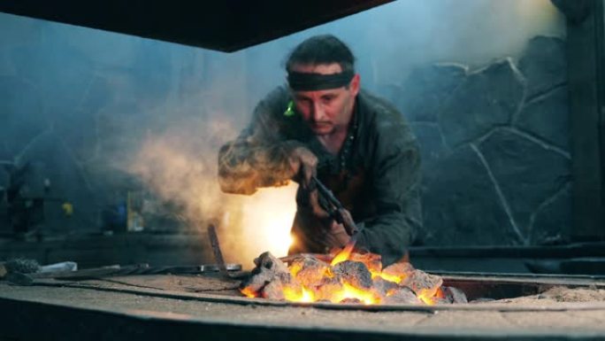 专业铁匠在火上加热刀。