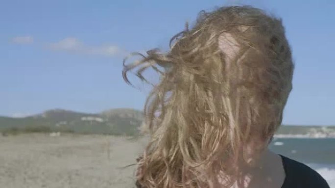 在大风天的海滩上，青少年的头发遮住了脸的慢动作视频