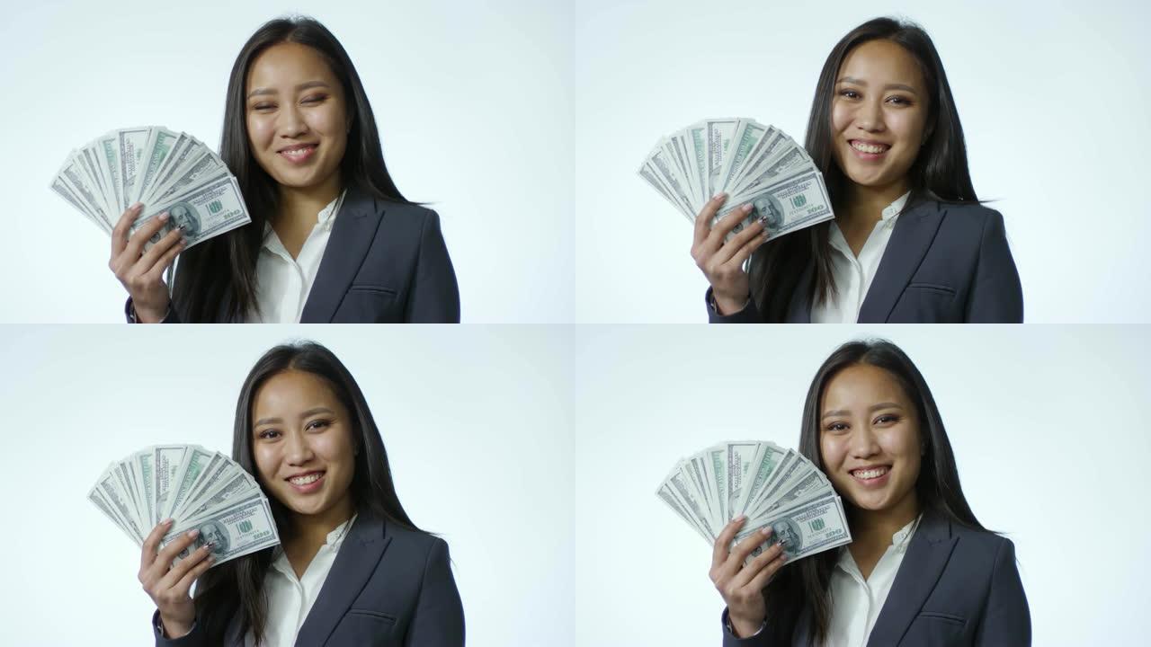 快乐的亚洲女商人在演播室与美元钞票粉丝合影