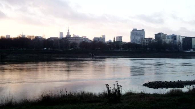 日落时分的河边。背景中的城市天际线