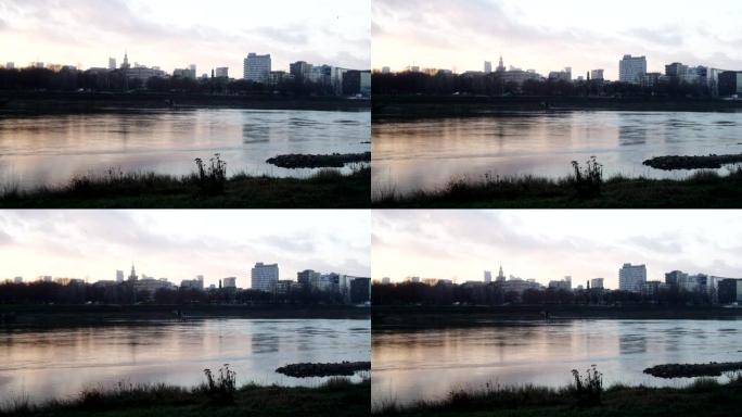 日落时分的河边。背景中的城市天际线