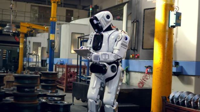 类人机器人正在工厂里用平板电脑工作