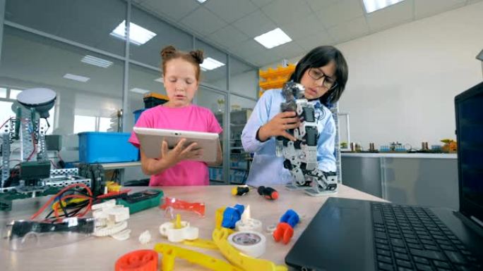 两个小学生在学校实验室里建造了一个塑料机器人。技术教育理念。