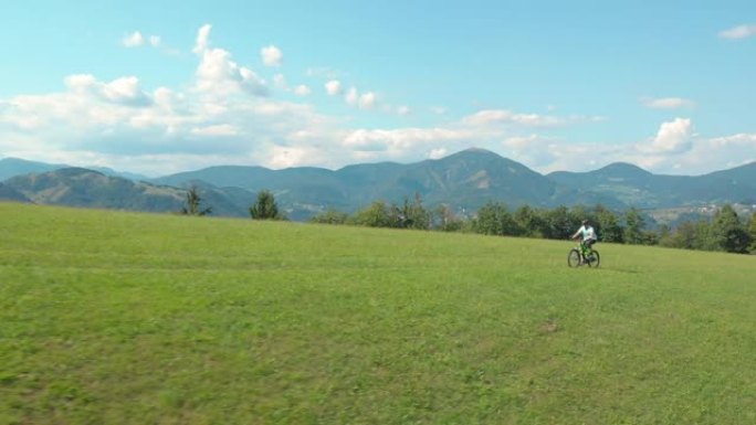 无人机: 运动型男子在草地上踩踏他的高科技电动自行车。