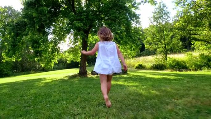 在一个美丽而快乐的阳光灿烂的日子里，一个打扮成超级英雄的小女孩在五彩缤纷的大自然中做出表情并试图飞翔