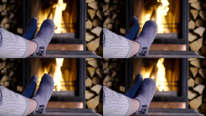 寒冷的秋天或冬天的晚上。人们用毯子和茶在炉火旁休息。穿着羊毛袜的脚的特写照片。舒适的场景。