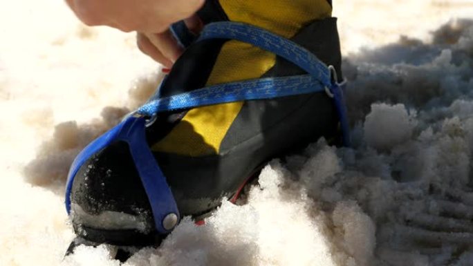 准备在雪地上攀登。将冰爪安装在靴子上