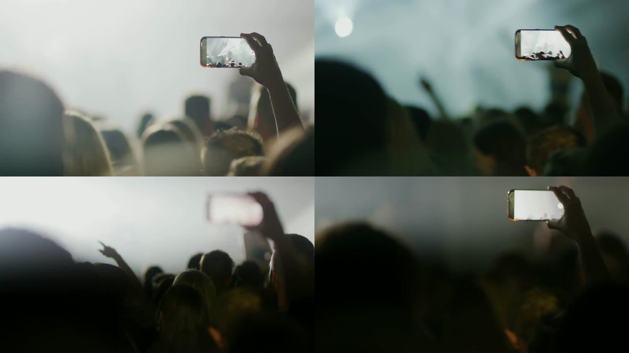男子女士带着照相手机拍摄音乐音乐会在人群中