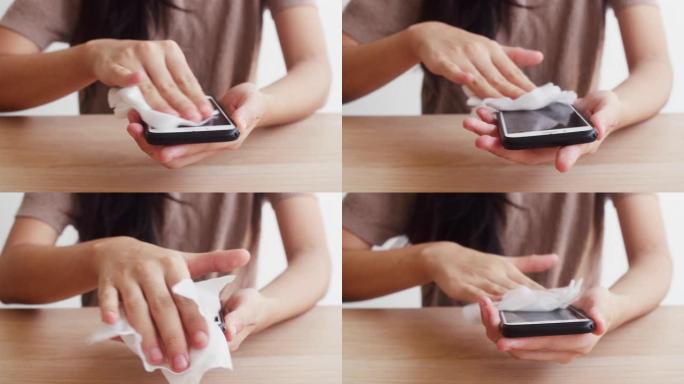 亚洲妇女使用酒精喷雾纸巾清洁手机使用前保护冠状病毒。