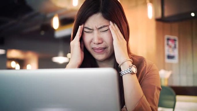 4k镜头亚洲女商人穿着休闲服在笔记本电脑前工作并患有抑郁症的场景-工作空间，商业健康和压力概念