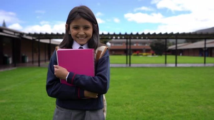 学校里开朗的小女孩拿着笔记本，对着镜头微笑