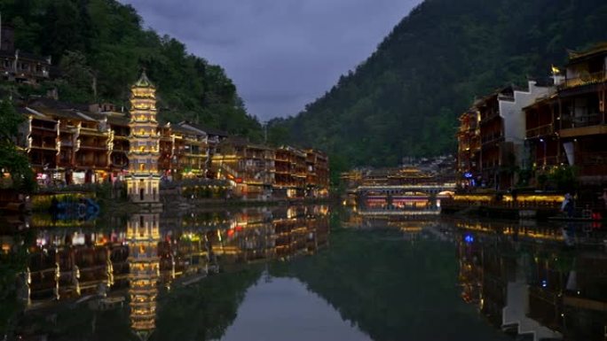 传统的中国塔和河两岸的房屋，黄昏时夜间照明。中国凤凰县古镇。“凤凰” 在中文里是 “凤凰鸟” 的意思