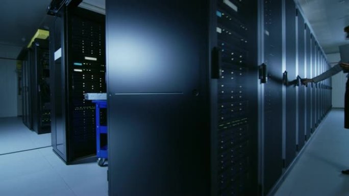 在现代数据中心: IT技术人员团队使用服务器机架，运行维护和诊断，检查网络和云计算的最佳功能。