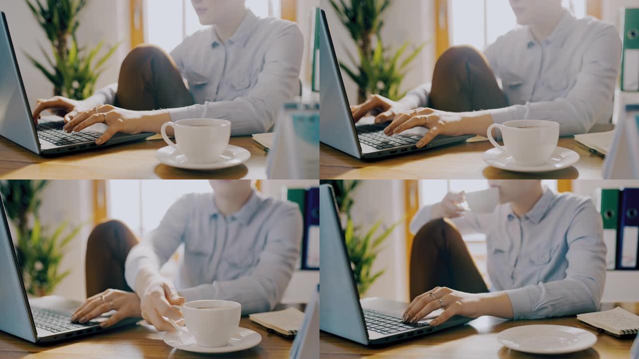 DS女人在家里用笔记本电脑工作时喝咖啡