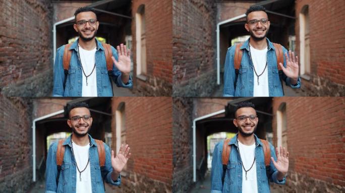友好开朗的阿拉伯男子在户外微笑着挥手的肖像