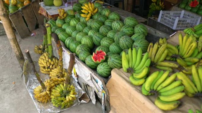 斯里兰卡路边市场摊位上展示的新鲜香蕉和西瓜女士