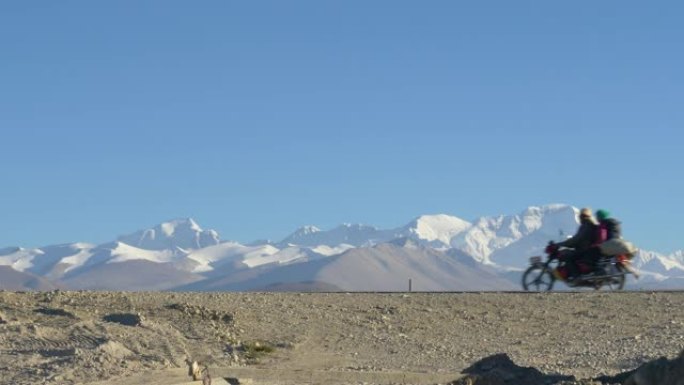 两名当地人骑着摩托车在一条空旷的道路上经过西藏的冰川