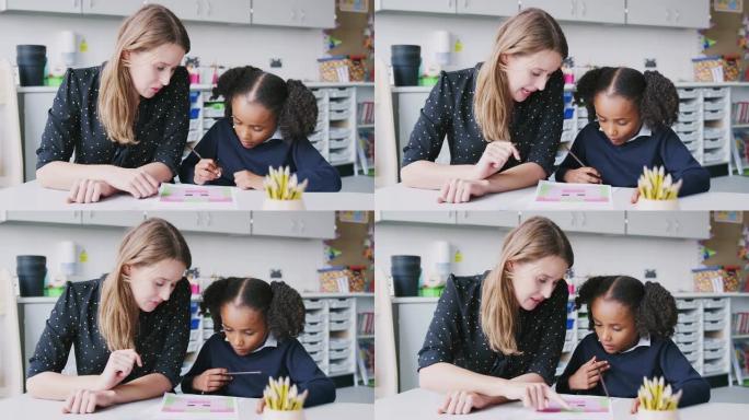 女小学教师与一名女学生在教室里一对一工作，特写