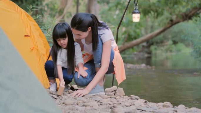 亚洲母亲通过露营教小女孩关于森林中的可持续性。快乐的家庭在户外一起。教孩子们关于可持续性，家庭，学习