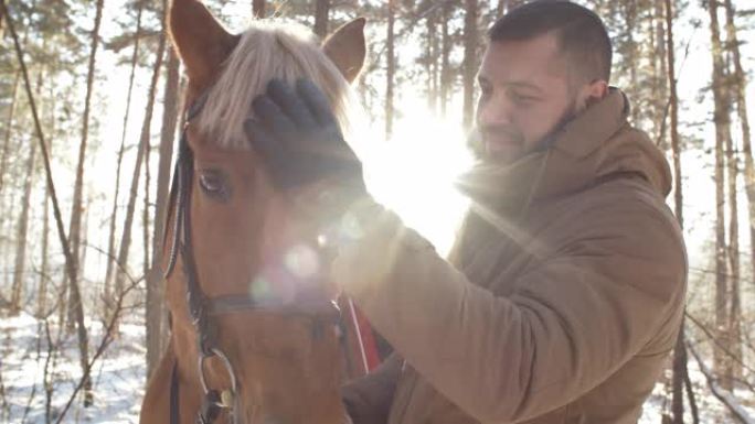 男人在冬季森林中爱抚马