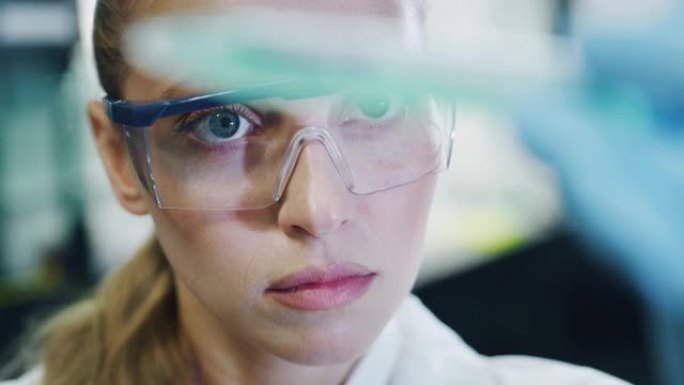 金发女科学家的肖像正在分析一种液体，以提取实验室试管中的DNA和分子