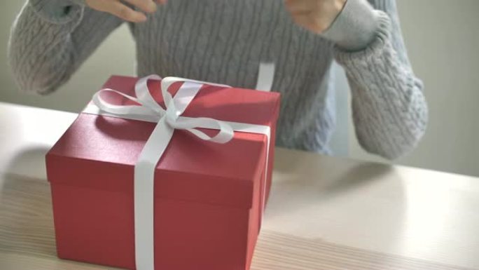 礼品包装。女人在情人节的红色盒子上绑白色缎带蝴蝶结