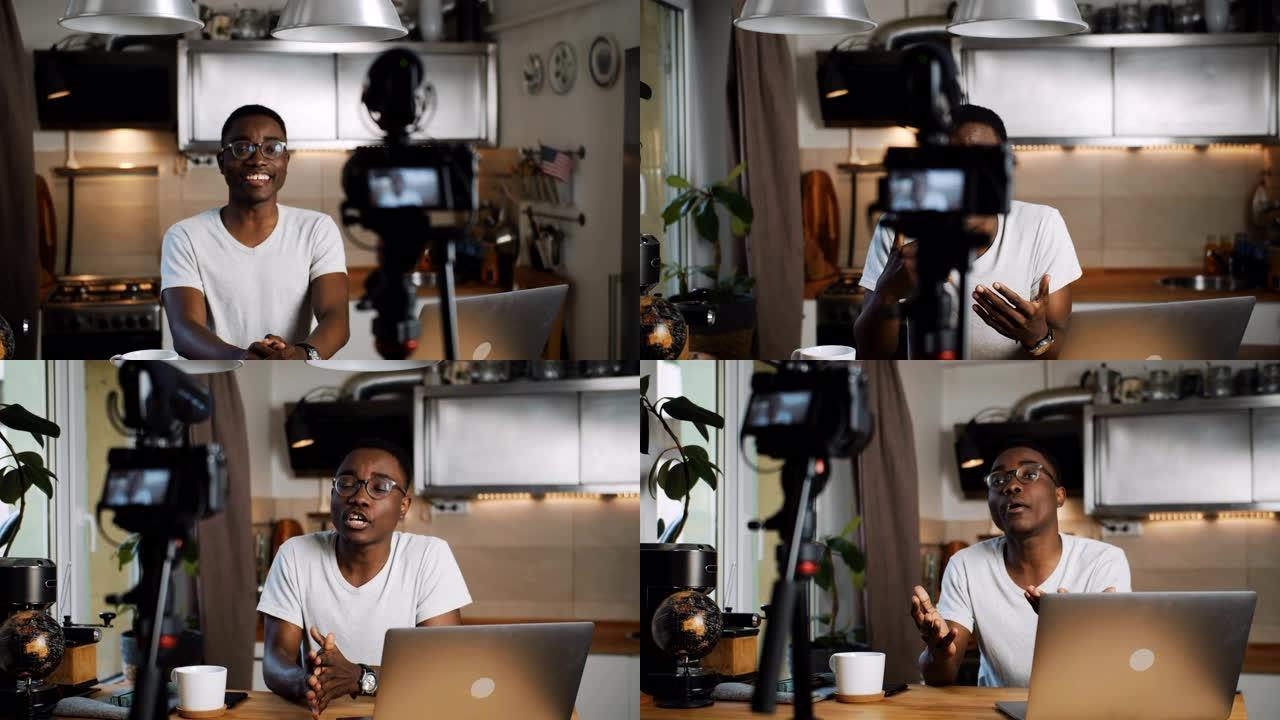 快乐的年轻聪明的黑人博主男子在家里的厨房用专业相机拍摄新的vlog视频慢动作。