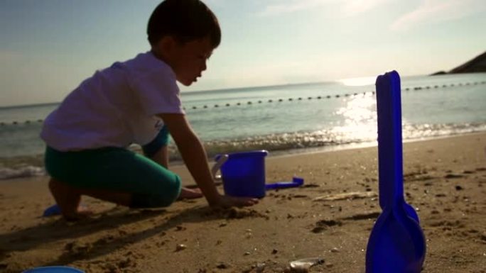 孩子的剪影早上在海滩上玩沙子。